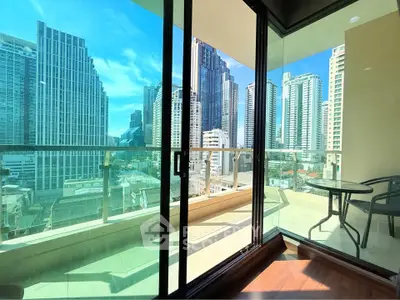 Stunning city view from modern balcony with glass doors and outdoor seating.