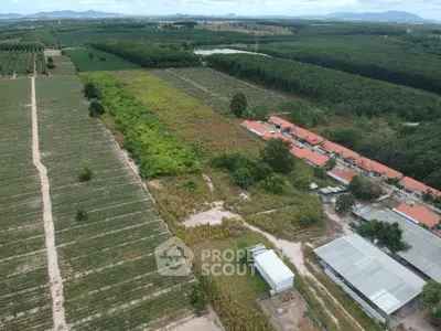 Expansive aerial view of lush farmland with adjacent residential buildings and scenic landscape.
