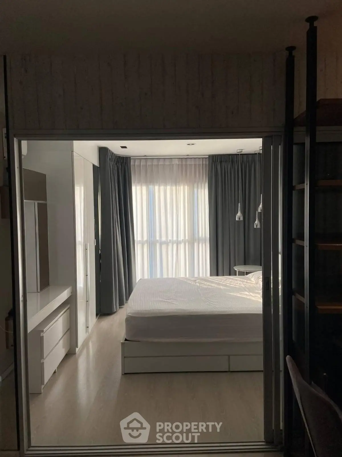 Modern bedroom with sleek design and natural light through large windows.