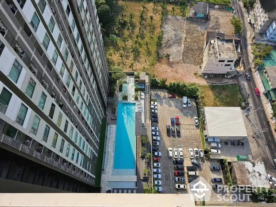 Stunning aerial view of modern high-rise building with pool and parking area, perfect urban living.