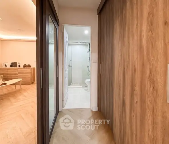 Modern apartment hallway leading to a sleek bathroom with wooden accents.