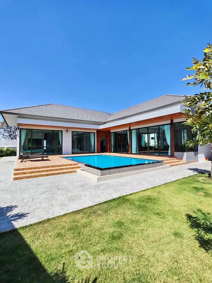 Luxurious modern villa with private pool and spacious garden under clear blue sky.