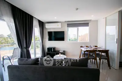 Modern living room with balcony view, sleek furniture, and natural light.