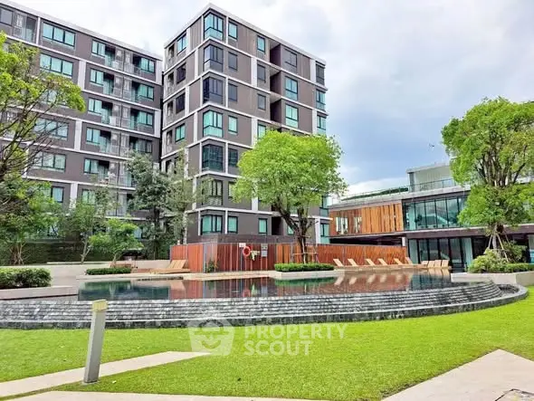 Modern apartment building with pool and lush garden view.