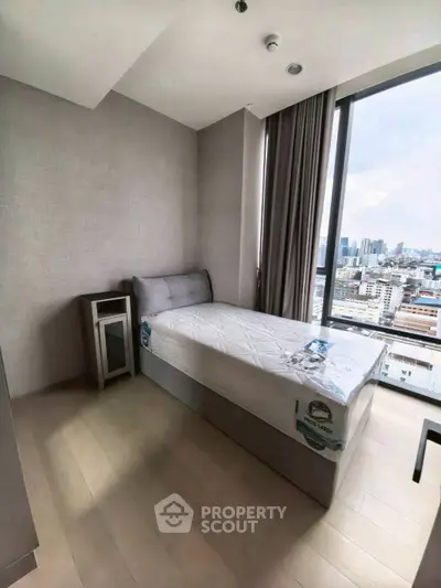 Modern bedroom with city view, featuring sleek design and large window for natural light.