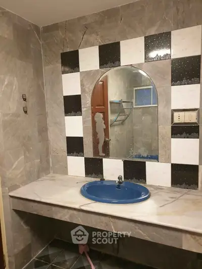 Elegant bathroom with marble countertop and blue sink, featuring stylish tile accents.