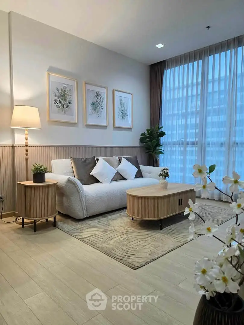 Elegant living room with modern decor, cozy sofa, and large window with sheer curtains.