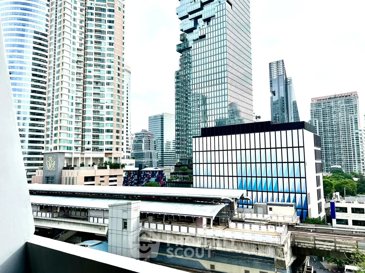 Stunning cityscape view from a high-rise balcony overlooking modern skyscrapers and urban transit.