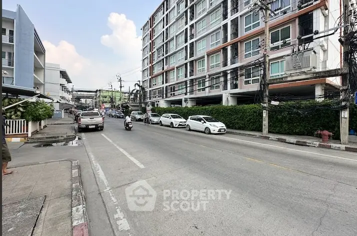 Modern urban apartment building with street view and parked cars, showcasing city living convenience.