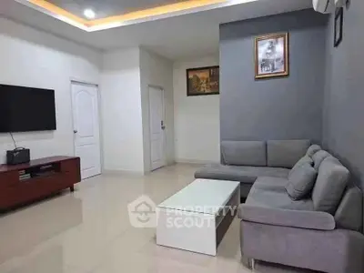 Modern living room with sleek gray sofa and wall-mounted TV, perfect for relaxation and entertainment.