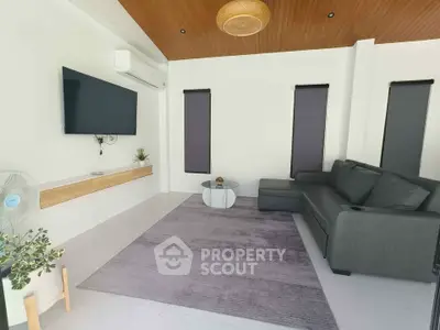 Modern living room with sleek furniture and minimalist decor, featuring a wall-mounted TV and stylish ceiling design.