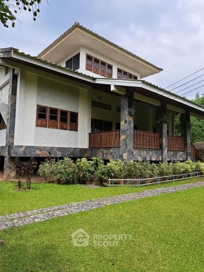 Charming two-story house with stone facade and lush green lawn, perfect for serene living.