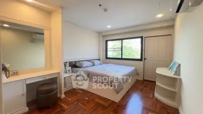 Spacious bedroom with elegant wood flooring and natural light