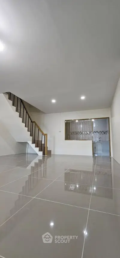 Spacious modern living room with sleek tile flooring and elegant staircase