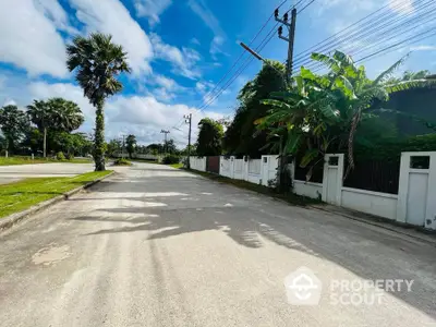 Scenic residential street with lush greenery and palm trees, perfect for tranquil living.