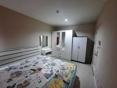 Cozy bedroom with modern white furniture and colorful bedding in a well-lit space.