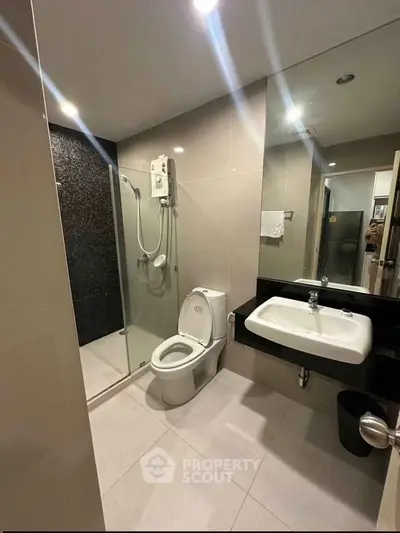 Modern bathroom with sleek fixtures and glass shower enclosure in a contemporary apartment.