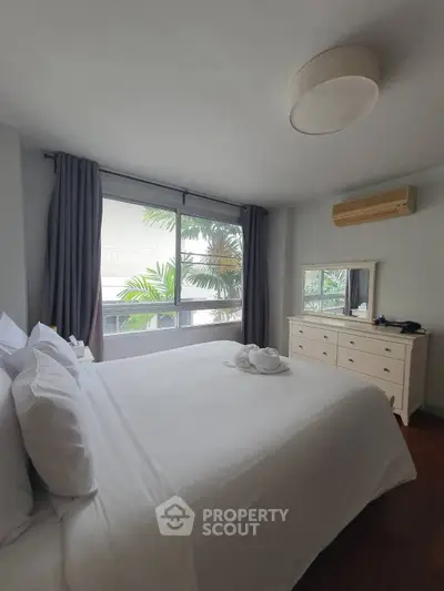 Spacious bedroom with large window and modern furnishings in a serene setting.
