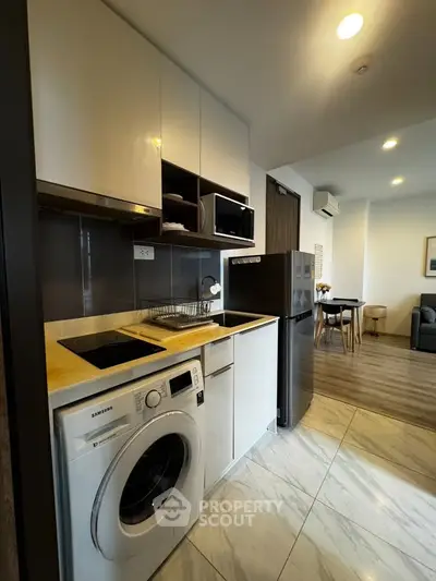 Modern kitchen with washing machine and sleek appliances in open layout apartment.