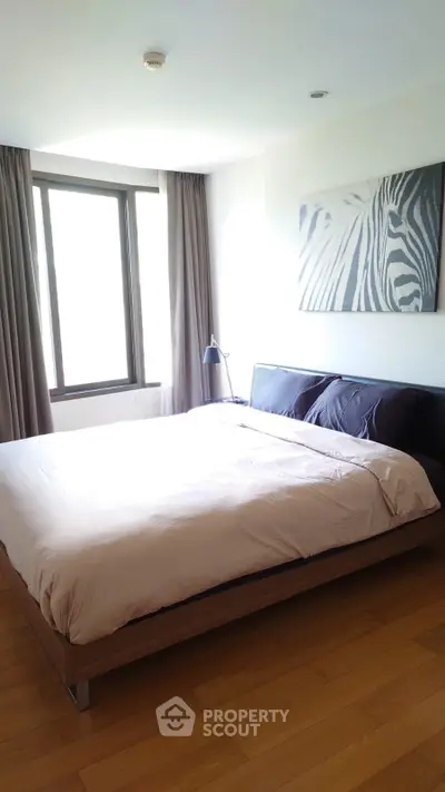 Modern bedroom with large window and zebra artwork, featuring a cozy bed and wooden flooring.