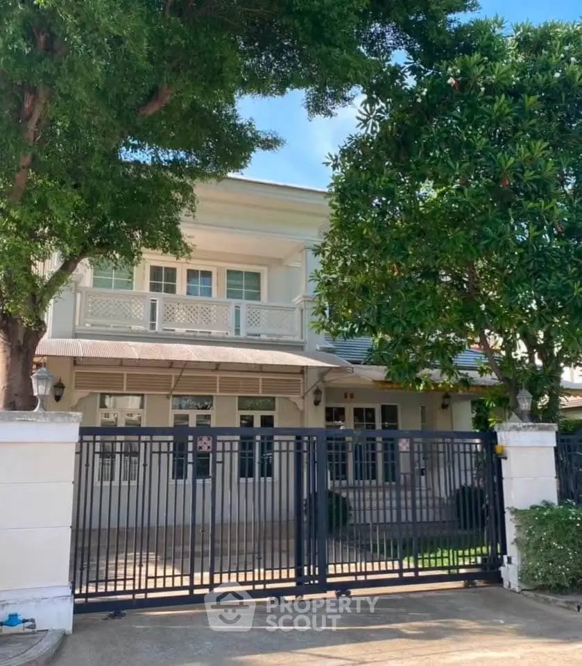 Charming two-story house with gated entrance and lush greenery