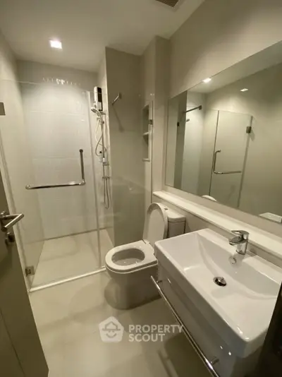 Modern bathroom with glass shower enclosure and sleek fixtures in a contemporary apartment.