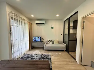 Modern living room with stylish decor, cozy sofa, and natural light from large windows.
