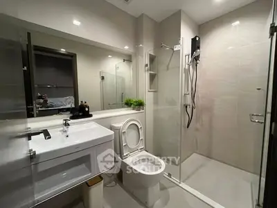 Modern bathroom with glass shower and sleek fixtures in contemporary apartment.