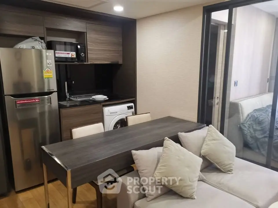 Modern compact kitchen with dining area and washing machine in cozy apartment.