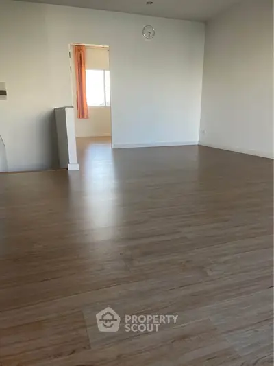 Spacious empty room with wooden flooring and white walls, ideal for customization.