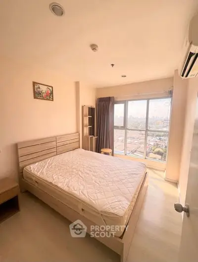 Bright bedroom with large window offering city views, featuring a comfortable bed and modern decor.