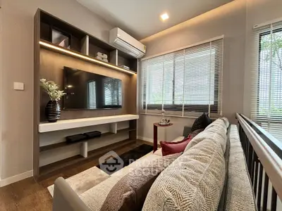 Modern living room with stylish decor and large TV, featuring cozy seating and natural light from large windows.