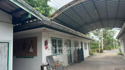 Charming rural property with covered outdoor area and lush greenery, perfect for serene living.