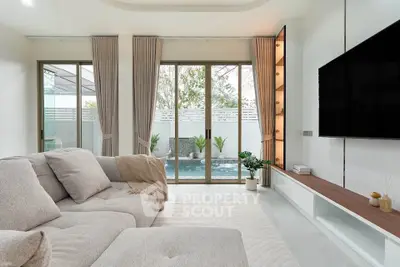 Modern living room with pool view, featuring cozy sofa and large TV, perfect for relaxation.