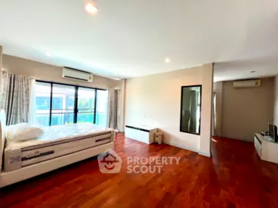 Spacious bedroom with wooden flooring and large windows in modern apartment