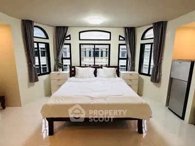 Spacious bedroom with large windows and modern decor in a luxury apartment.
