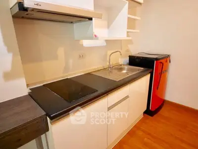 Modern compact kitchen with sleek design and vibrant red fridge
