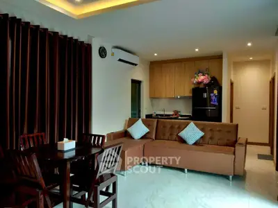 Modern living room with open kitchen, stylish furniture, and ambient lighting.