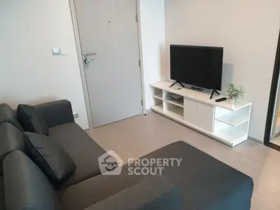 Modern living room with sleek gray sofa and flat-screen TV on white stand.