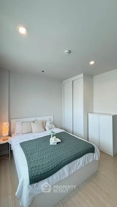 Modern bedroom with cozy decor and ample natural light, featuring a stylish bed and sleek storage solutions.