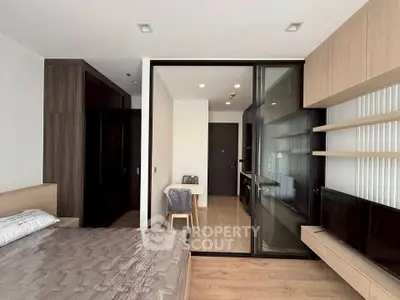 Modern bedroom with sleek design, featuring a glass partition and built-in storage solutions.