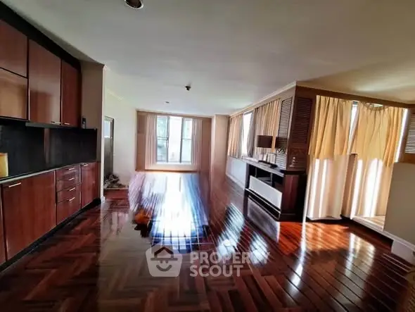 Spacious living room with polished wooden floors and ample natural light