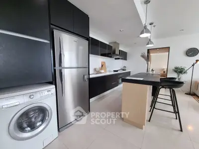 Modern kitchen with sleek black cabinets, stainless steel appliances, and a washing machine.
