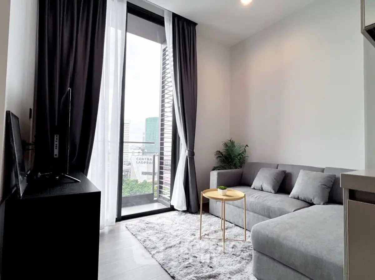 Modern living room with gray sectional sofa and balcony view in a stylish apartment.