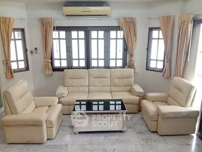 Spacious living room with elegant cream leather sofas and large windows for natural light.