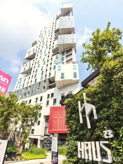 Modern high-rise building with unique architecture and lush greenery in urban setting.