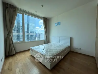 Spacious bedroom with large windows offering stunning city views in modern apartment.