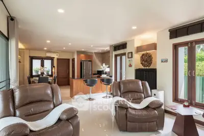 Spacious living room with modern leather sofas and open kitchen layout in a stylish home.