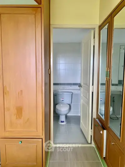 Cozy bathroom view from hallway with wooden cabinets and tiled flooring