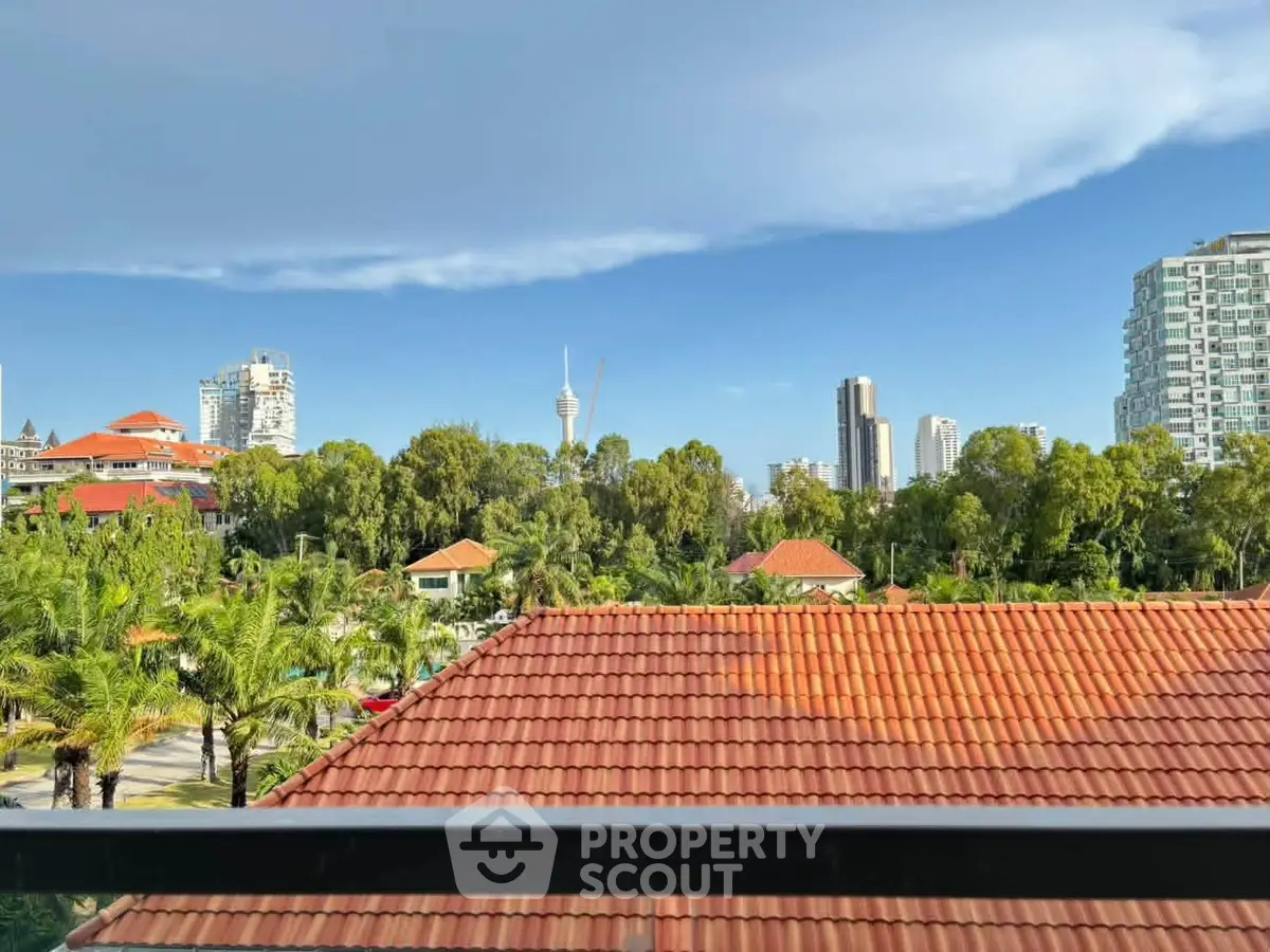 Stunning cityscape view from a balcony overlooking lush greenery and modern skyline.